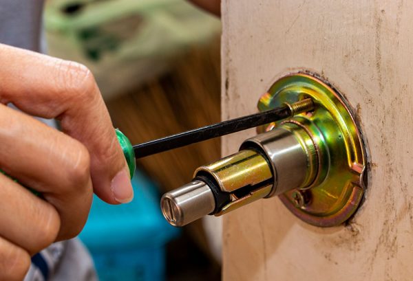 locksmith-is-repairing-wooden-door-knob-with-screwdriver